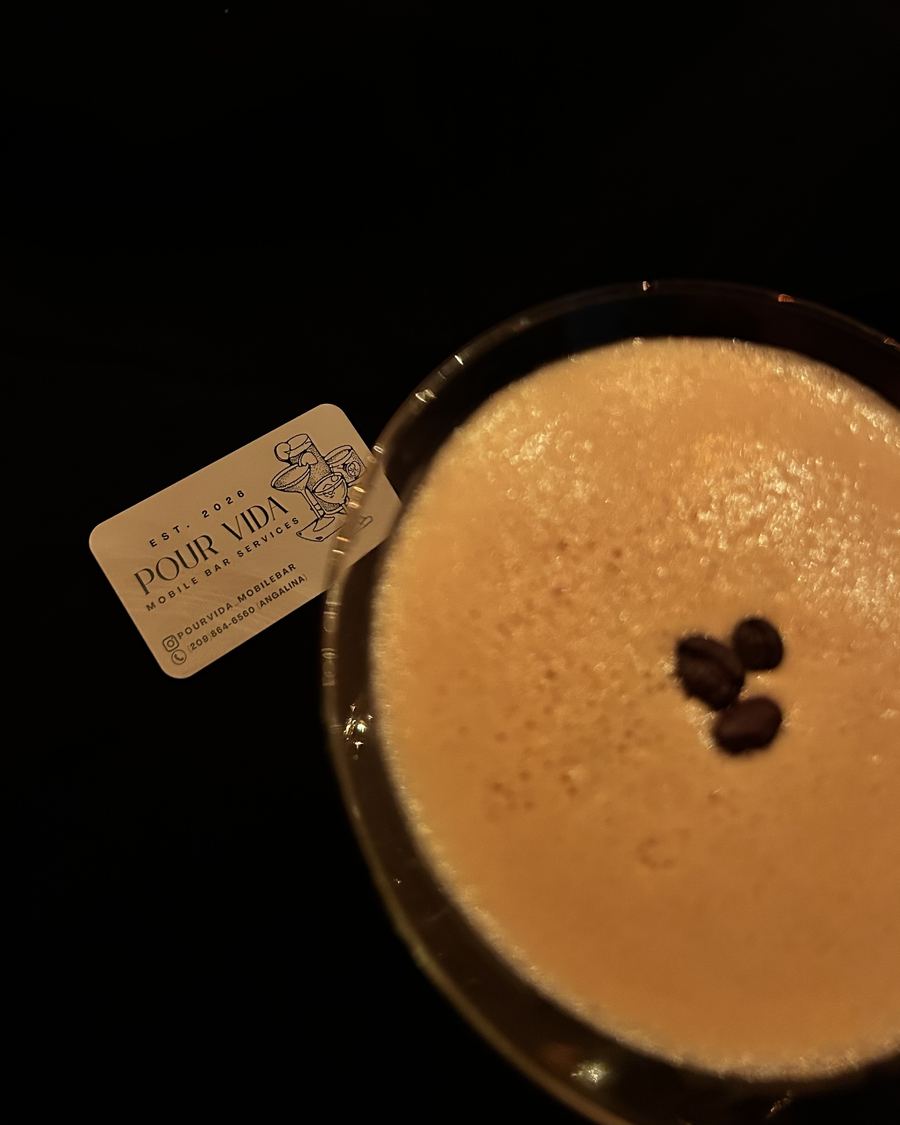 Close-up from above of an espresso martini's foam and coffee beans